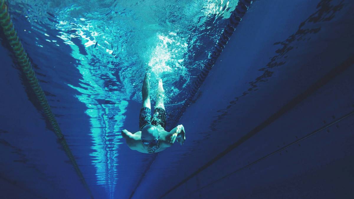 Man performing freestyle stroke in lap pool demonstrating swimming health benefits for men