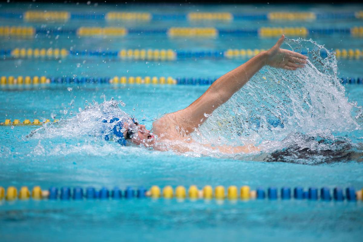 Swimmer performing dryland core exercise on pool deck with resistance band — exercises to help swimming