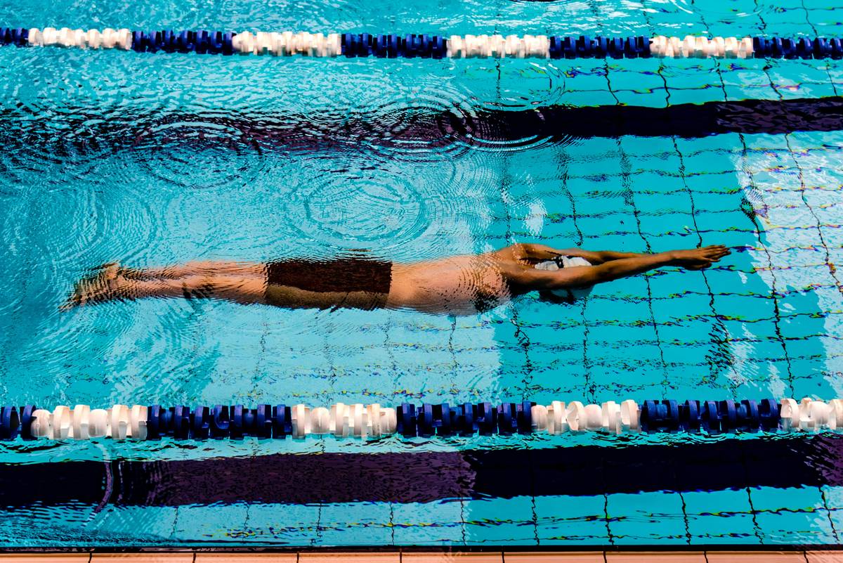 A beginner practicing learn to swim techniques with a kickboard in a pool