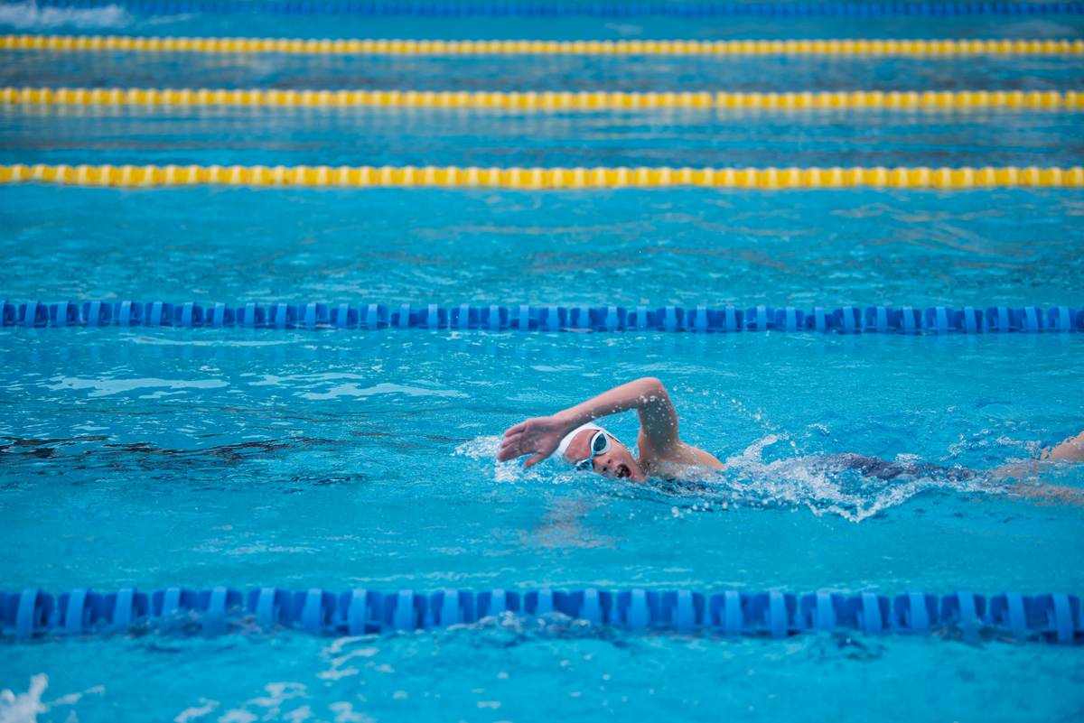 swimming health benefits for women – woman performing freestyle stroke in calm pool water